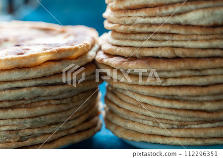 Flatbread lavash, chapati, naan, heap of tortilla on a blue background Homemade flatbread stacked. Flatbread lavash, chapati, naan, heap of tortilla on a blue background Homemade flatbread stacked. 112296351
