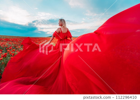 Woman poppy field red dress. Happy woman in a long red dress in a beautiful large poppy field. Blond stands with her back posing on a large field of red poppies Woman poppy field red dress. Happy woman in a long red dress in a beautiful large poppy field. Blond stands with her back posing on a large field of red poppies 112296410