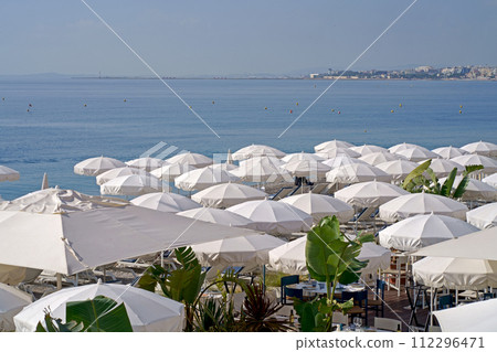 France. Nice. Nice beach with beach chairs, white umbrellas and palm trees. luxury beach against the background of the beauty of the sea. summer holiday 112296471
