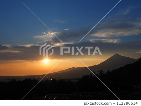 The contrast between the orange sun and sky below the dark clouds and the silhouette of Mt. Bandai is impressive and beautiful. 112296614