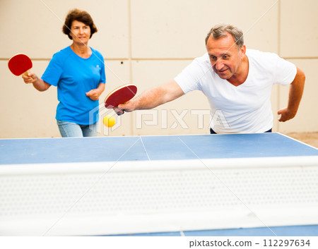 Happy mature man and woman playing table tennis Happy mature man and woman playing table tennis 112297634