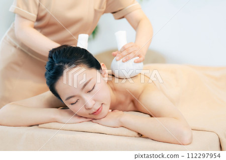 woman receiving herbal massage 112297954