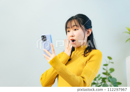 A woman surprised to see a smartphone A woman surprised to see a smartphone 112297967