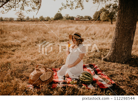 happy European caucasian pregnant woman relaxing in nature picnic looking at camera. 112298544