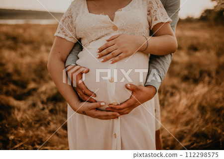 hands of future mother and father clasped pregnant big tummy. 112298575