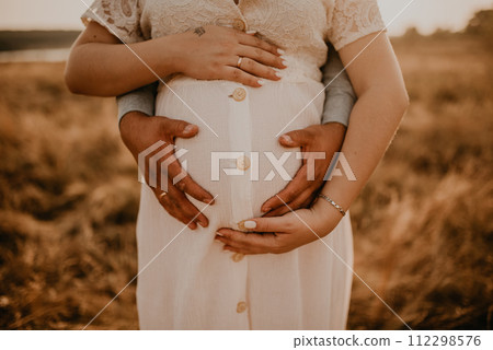 hands of future mother and father clasped pregnant big tummy. 112298576