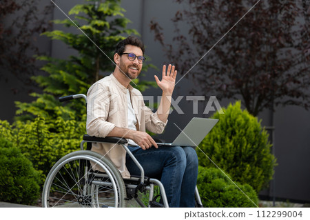 Young bearded man in a wheelchair working on laptop 112299004