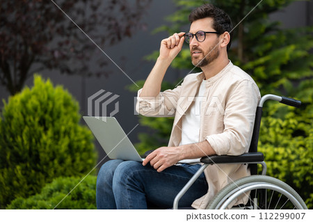 Young bearded man in a wheelchair working on laptop 112299007
