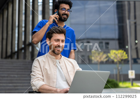 Disabled self-employed man working on laptop while sitting in wheelchair in hospital yard 112299025