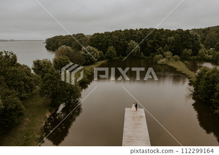 Newlyweds kissing hugging on wooden pier bridge on lake. aerial view drone 112299164