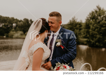 Newlyweds kissing hugging on wooden pier bridge on lake 112299166