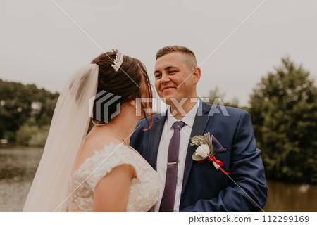 Newlyweds hold hands and look at each other near river Newlyweds hold hands and look at each other near river 112299169
