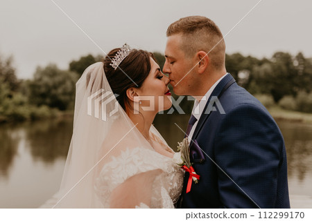 Newlyweds hold hands and look at each other near river Newlyweds hold hands and look at each other near river 112299170
