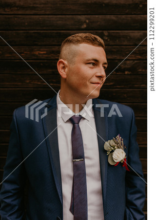 Caucasian young man groom in navy blue suit white shirt and tie looking to the side. Caucasian young man groom in navy blue suit white shirt and tie looking to the side. 112299201