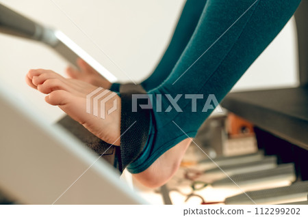 Woman legs on reformer machine for full-body Pilates workout 112299202