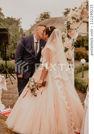 wedding ceremony on the background of a flower arch laughing kissing wedding ceremony on the background of a flower arch laughing kissing 112299235