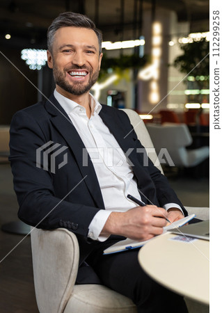 Smiling elegant businessman working and looking contented 112299258