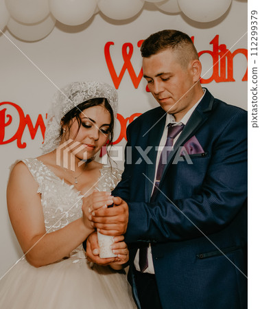 groom bride shawl are holding together in their hands a lighted candle symbolizes the family hearth 112299379