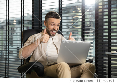 Young bearded man in casual clothes working on laptop Young bearded man in casual clothes working on laptop 112299391