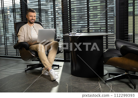 Young bearded man in casual clothes working on laptop 112299393