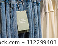 Eco-friendly jeans with an information tag saying that the jeans are made with 20% recycled cotton. 112299401