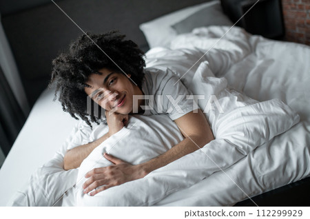 Young man lying in bed and looking relaxed 112299929