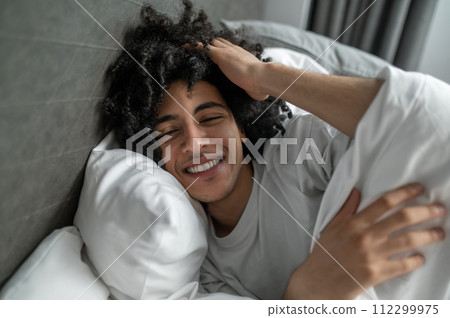 Young brunette man lying in bed and looking sleepy Young brunette man lying in bed and looking sleepy 112299975