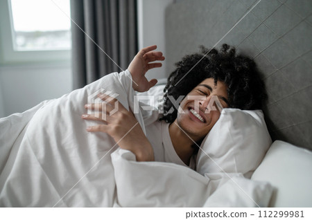 Young brunette man lying in bed and looking sleepy Young brunette man lying in bed and looking sleepy 112299981