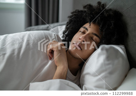 Curly-haired young man sleeping and looking peaceful Curly-haired young man sleeping and looking peaceful 112299988