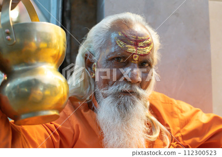 Ascetic monk Sadhu in India with beard, white hair and painted face preaching Ascetic monk Sadhu in India with beard, white hair and painted face preaching 112300523