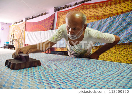 Artisan stamping patterns in ink on traditional Indian textiles as colorful sari Artisan stamping patterns in ink on traditional Indian textiles as colorful sari 112300530