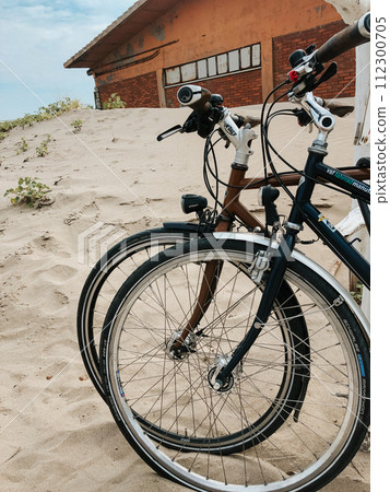 two sports bikes stand side by side on white sandy beach. two sports bikes stand side by side on white sandy beach. 112300705