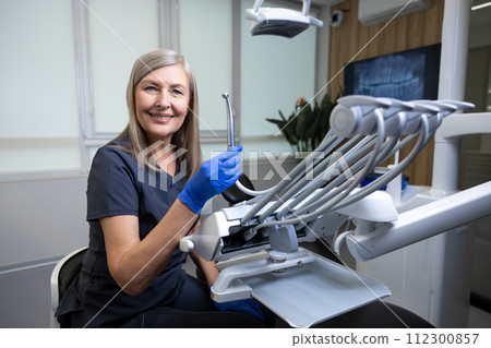 Female dentist wearing uniform sitting in her doctors room 112300857