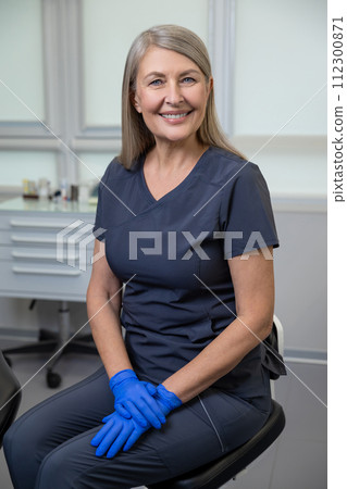 Female dentist wearing uniform sitting in her doctors room 112300871