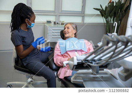 Woman patient sitting in dental chair at medical center while professional doctor fixing her teeth 112300882