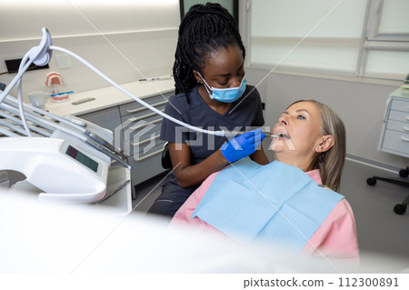 Woman visiting dentistry clinic for professional teeth treatment doctor holding instrument tool 112300891