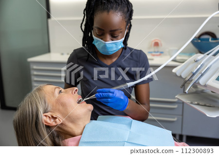 Woman patient sitting in dental chair at medical center while professional doctor fixing her teeth 112300893