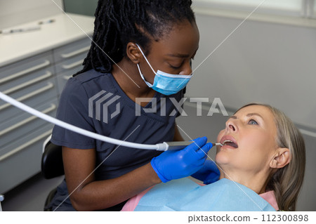 Woman patient sitting in dental chair at medical center while professional doctor fixing her teeth 112300898