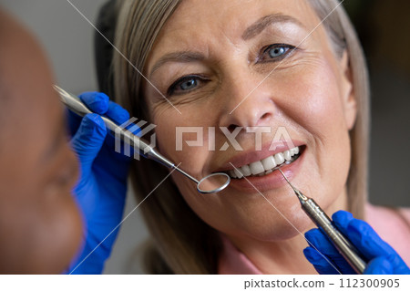 Woman visiting dentistry clinic for professional teeth treatment doctor holding instrument tool Woman visiting dentistry clinic for professional teeth treatment doctor holding instrument tool 112300905
