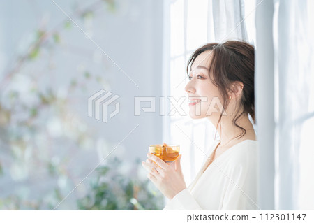 A woman who drinks tea at the window side 112301147