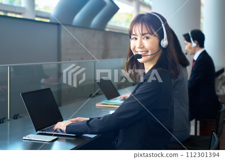 辦公室裡戴著耳機的相應套裝的操作員 112301394