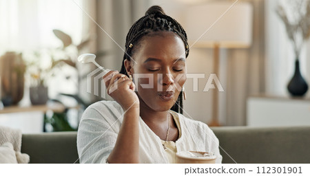Black woman on sofa, eating ice cream and relax in living room with smile, summer pleasure and enjoy. Happiness, fun or thinking, girl on couch with taste of frozen chocolate getalo dessert in home. 112301901