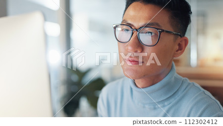 Asian man at computer, glasses and reflection, thinking and reading email, review or article at digital agency. Internet, research and businessman at tech startup with report, networking or feedback. 112302412