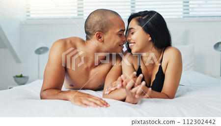 Happy couple, relax and kissing on bed for intimacy, morning romance or love in embrace, trust or care at home. Young man and woman smile lying in bedroom for passion or bonding together at house Happy couple, relax and kissing on bed for intimacy, morning romance or love in embrace, trust or care at home. Young man and woman smile lying in bedroom for passion or bonding together at house 112302442