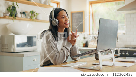 Laptop, headphones and video call with a woman entrepreneur in the kitchen of her home for small business. Computer, virtual meeting and a young freelance employee remote working from her house Laptop, headphones and video call with a woman entrepreneur in the kitchen of her home for small business. Computer, virtual meeting and a young freelance employee remote working from her house 112302455