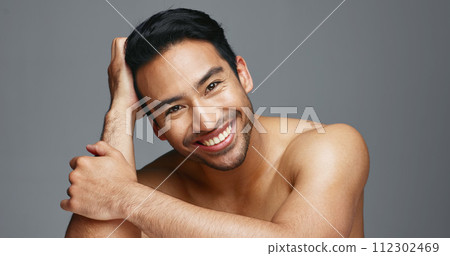 Face, cosmetics and Asian man with skincare, smile and dermatology on a grey studio background. Portrait, Japanese person and happy model with wellness, luxury treatment and beauty with aesthetic 112302469