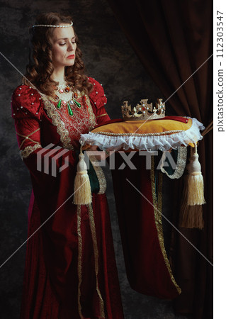 medieval queen in red dress with crown on pillow 112303547