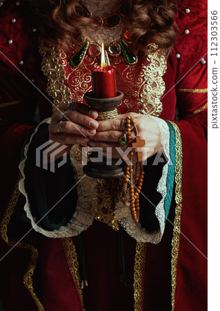 Closeup on medieval queen in red dress with candle Closeup on medieval queen in red dress with candle 112303566