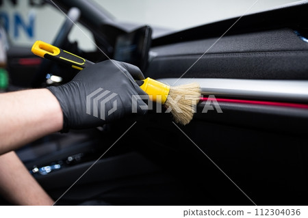Car wash or car detailing studio worker carefully cleaning car interior 112304036