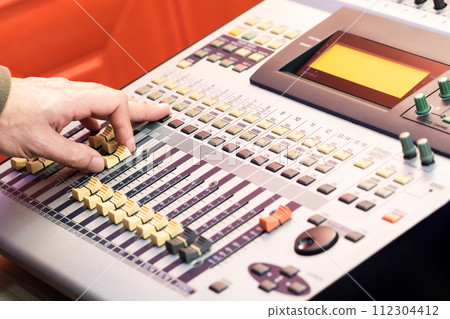 male sound engineer hand working on audio mixing console. recording concept 112304412